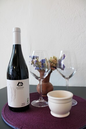 Une bouteille de vin, deux verres à vin et un bol sur une table.
