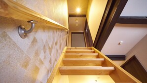 Eine hölzerne Treppe mit Handlauf, die zu einer Tür oben führt.