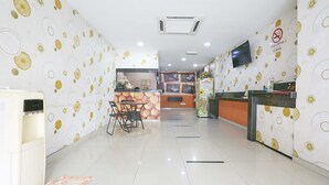 A clean, modern reception area with a counter, seating, and a wall-mounted TV. - Hotel O Orange Hotel Kuala Pilah (Kuala Pilah)