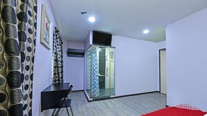 A bedroom with a bed, a desk, a chair, a wardrobe, and a shower area. - Hotel O Orange Hotel Kuala Pilah (Kuala Pilah)