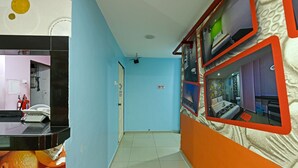 A hallway with a blue wall, a black counter with a white appliance, and a ceiling fan. - Hotel O Orange Hotel Kuala Pilah (Kuala Pilah)