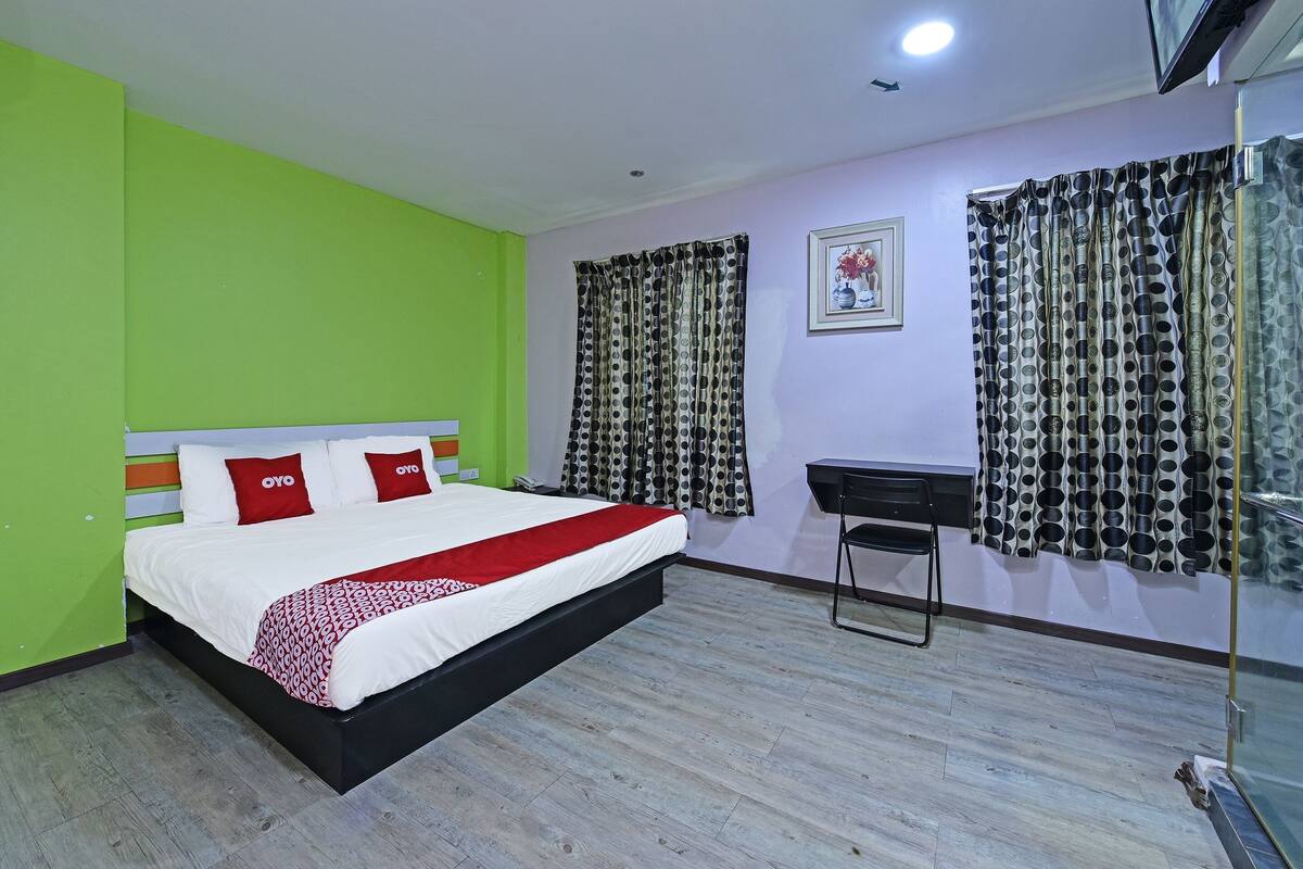 A hotel room with a bed, a desk, and curtains.