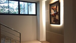 Un interior moderno con una escalera, una obra de arte enmarcada en la pared y una ventana que ofrece vistas a edificios y árboles.