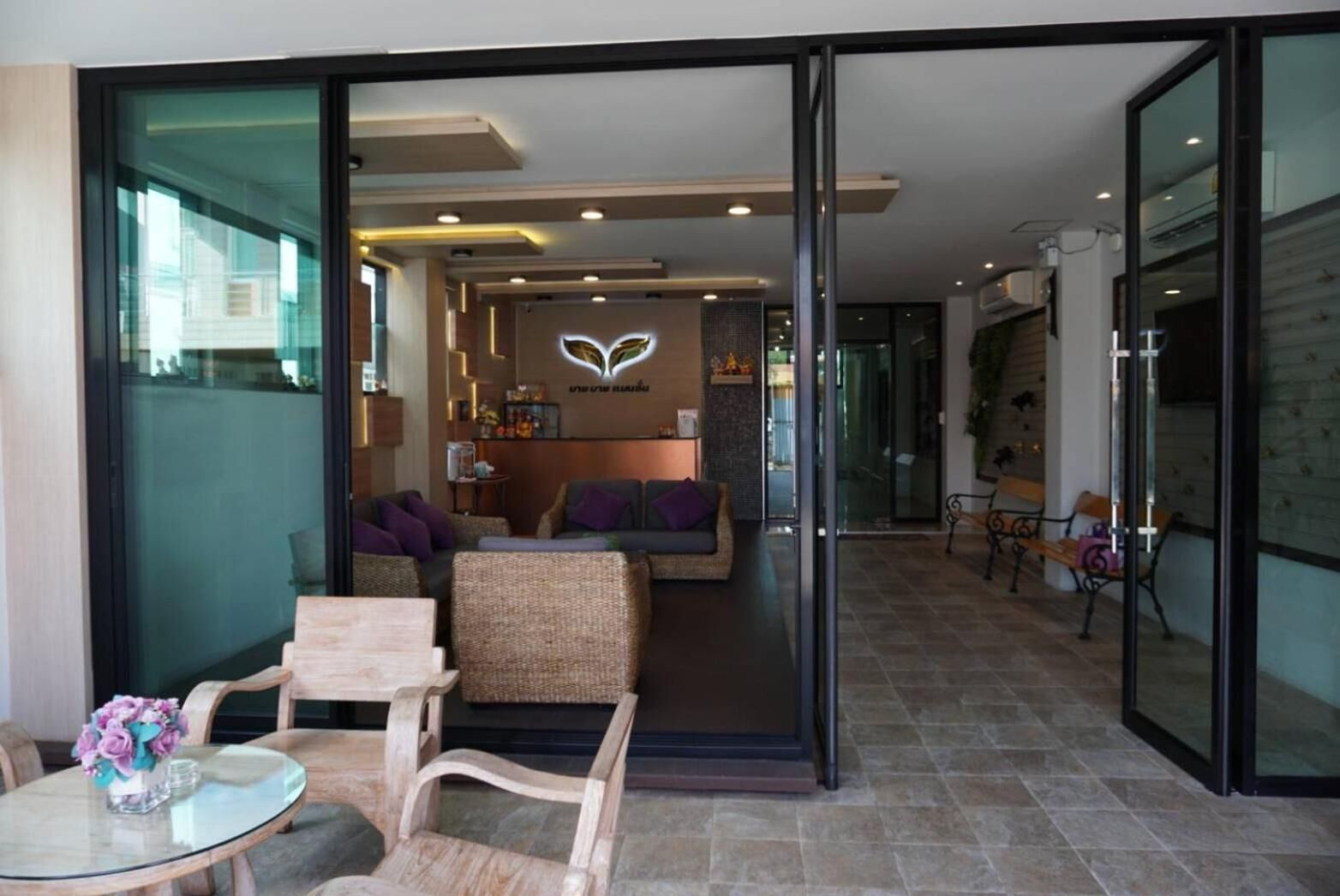A modern hotel lobby with a reception desk, seating area, and a glass partition.