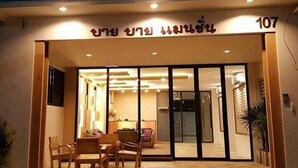 Entrada de un hotel con mostrador de recepción, zona de estar y una escalera que conduce al interior.