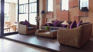 Una sala de estar moderna con mobiliario de mimbre, ventanas amplias y un diseño minimalista.