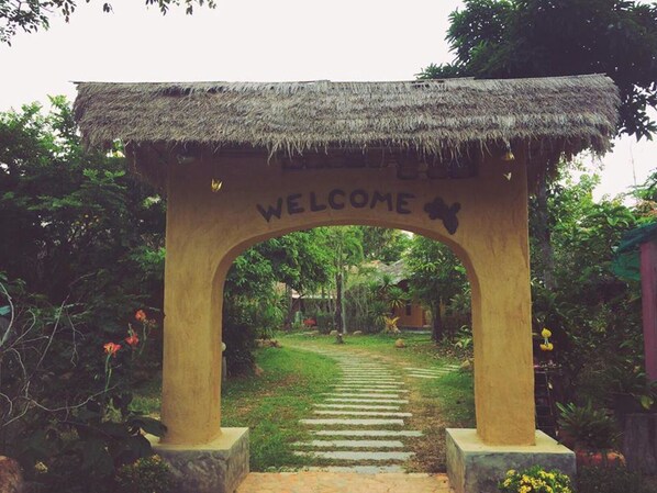 A welcoming archway with a thatched roof and the word "WELCOME" inscribed on it.