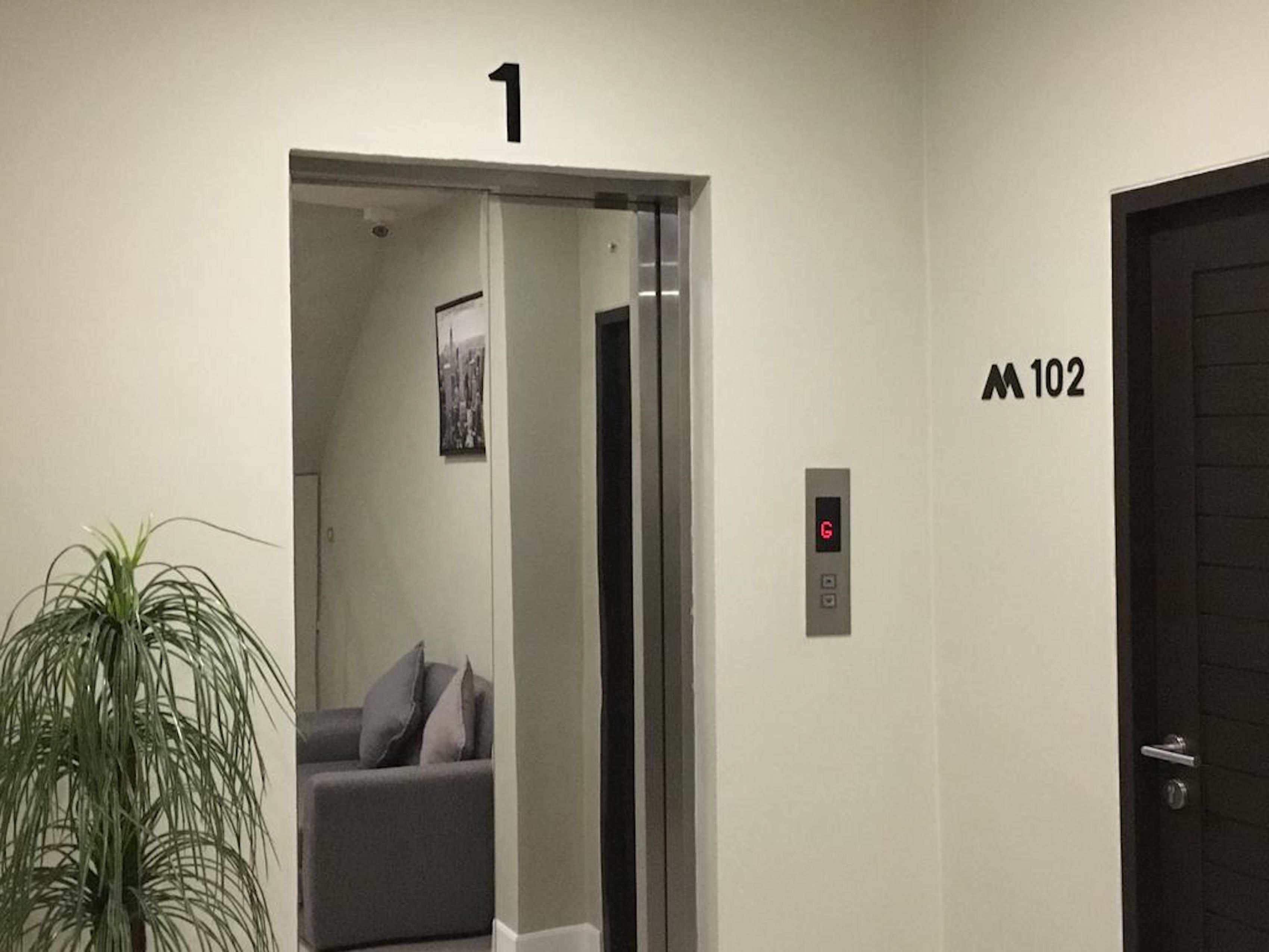 Un ascensor con una pantalla digital, una puerta marcada con el número 1 y una puerta marcada con el número 102.