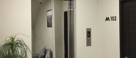 Un ascensor con una pantalla digital, una puerta marcada con el número 1 y una puerta marcada con el número 102.