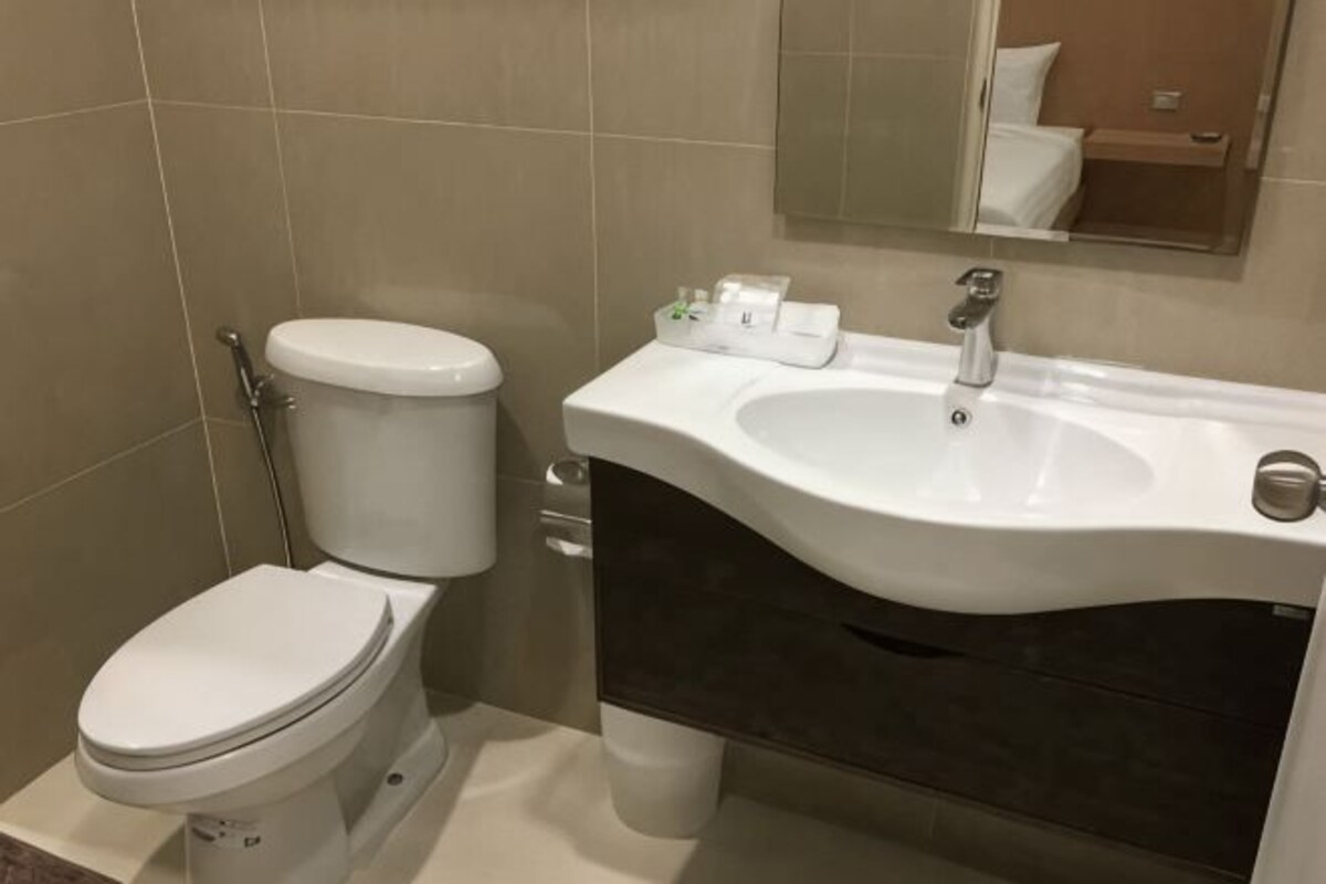 A bathroom with a toilet, sink, and mirror.