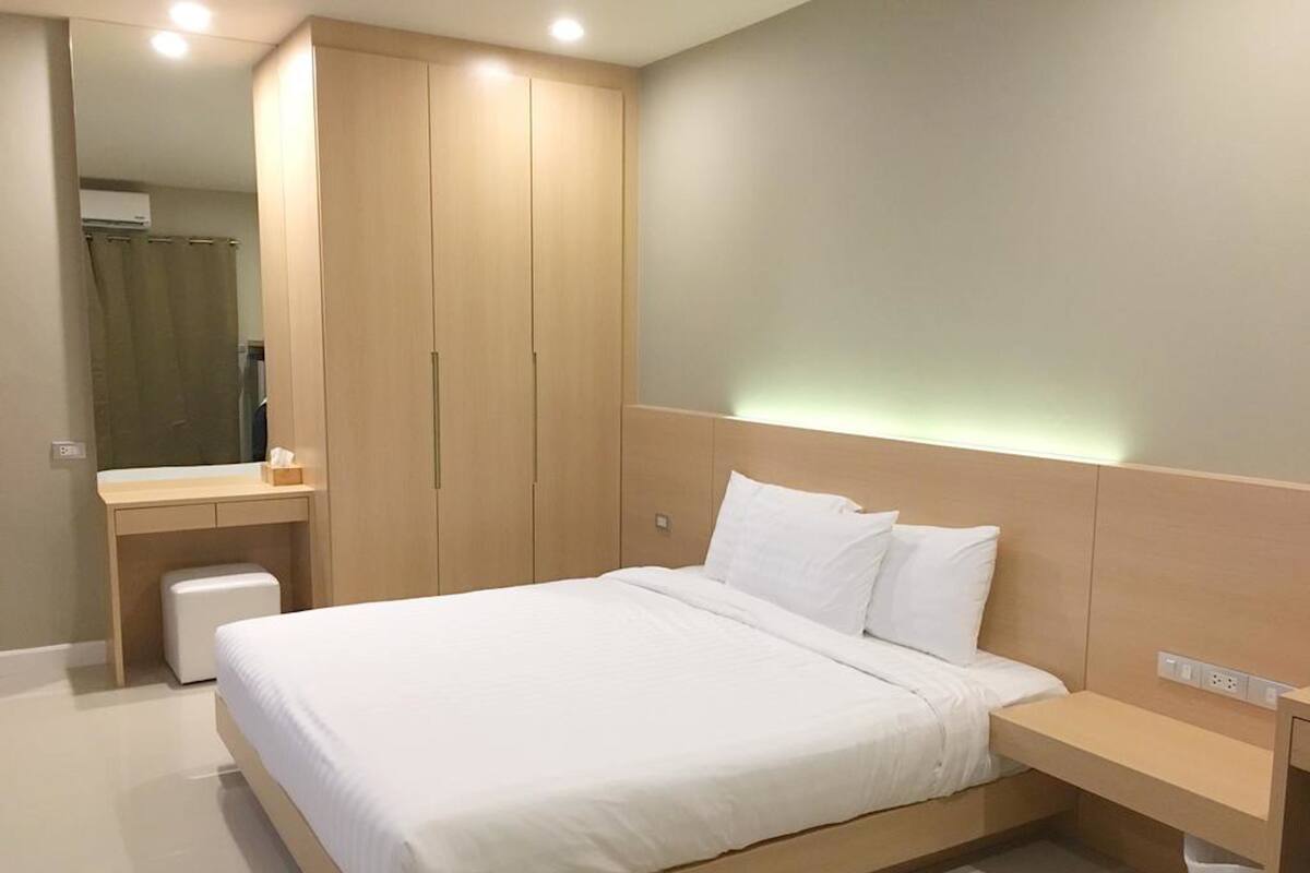 Une chambre à coucher moderne avec un lit, une table de chevet et une armoire.