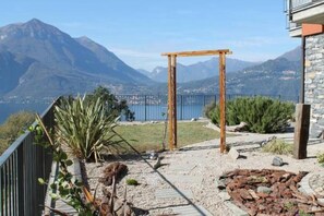 A patio with a wooden pergola, a view of mountains, and a body of water.