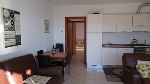 A compact living space with a dining area, a kitchenette, and a sofa.