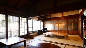 A traditional Japanese room with tatami flooring, a low wooden table, a bench, and sliding doors. - Asuka Guest House - Hostel (Asuka)