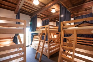 A room with bunk beds, wooden beams, and a window with curtains. - Asuka Guest House - Hostel (Asuka)