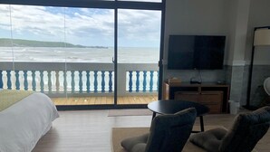 Une chambre d’hôtel dotée d’un grand balcon, d’un lit, d’une télévision et d’un coin salon.