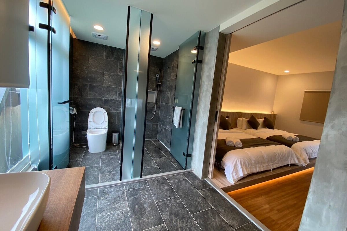 Een moderne hotelkamer met een douche, toilet en een bed met netjes opgemaakte lakens.