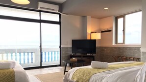 Une chambre d’hôtel avec deux lits, une télévision, un balcon avec vue et une petite table.