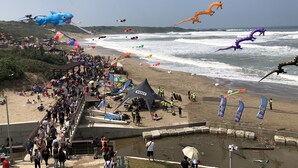 Une plage bondée, avec des tentes et une jetée.
