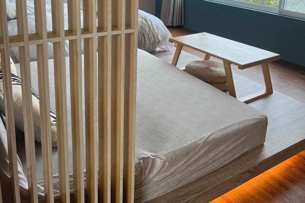 Een moderne slaapkamer met een bed, een klein tafeltje en uitzicht op zee door een groot raam.