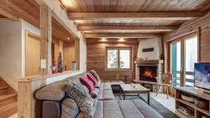 A cozy living room with a wooden ceiling, a fireplace, a sofa, and a television. - Chalet les Marmottes - La Tzoumaz, 4 Vallees (La Tzoumaz)
