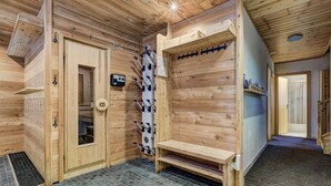A wooden sauna room with a bench, a sauna door, and a towel rack. - Chalet les Marmottes - La Tzoumaz, 4 Vallees (La Tzoumaz)