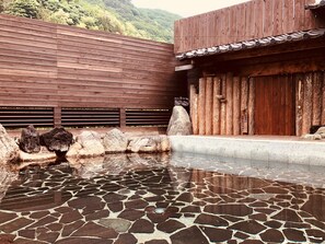 A traditional wooden building with a tiled roof and a stone-tiled pool area. - Hotel Ichiyotei (Minakami)