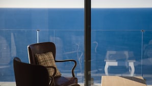 Een stoel met een ruitkussen op een balkon met uitzicht op zee.