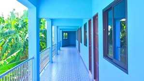 Un pasillo con paredes azules y suelo de baldosas, que conduce a una puerta al final.