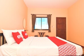 Een hotelkamer met een bed, een raam met gordijnen, een klein tafeltje en een deur.