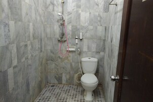 Un baño con inodoro, ducha y pared de mármol.