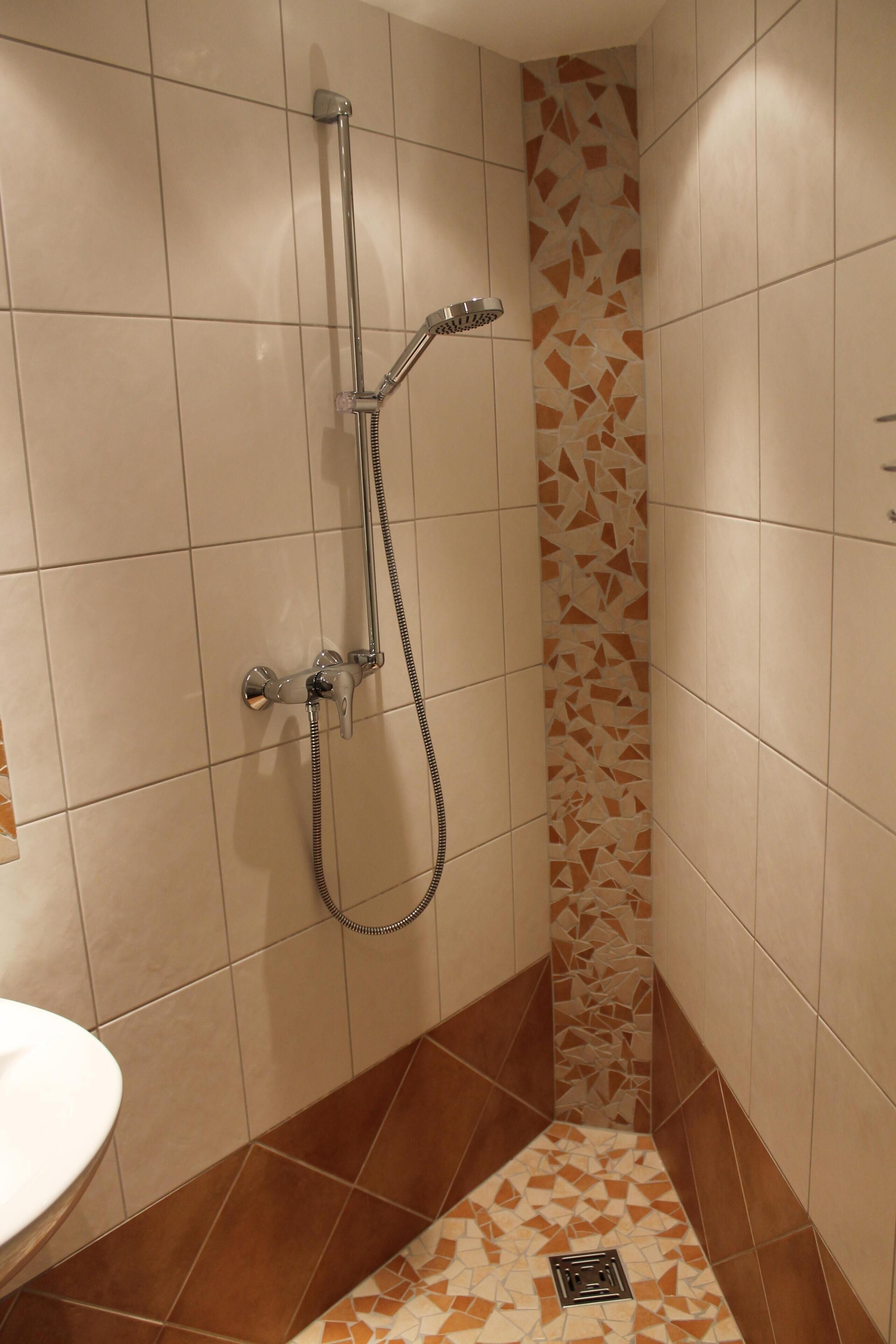 A bathroom with a shower, tiled walls, and a sink.