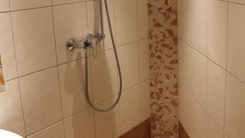 A bathroom with a shower, tiled walls, and a sink.