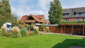 A residential area with a well-maintained lawn, a wooden deck, and a covered bike parking area. - Casa mia: Gloria - Beautiful apartment with fireplace and terrace/ 2 bedrooms 2 bathrooms (Borkum)