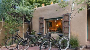 Un edificio con fachada rústica, una ventana con persianas de madera y dos bicicletas estacionadas adelante.