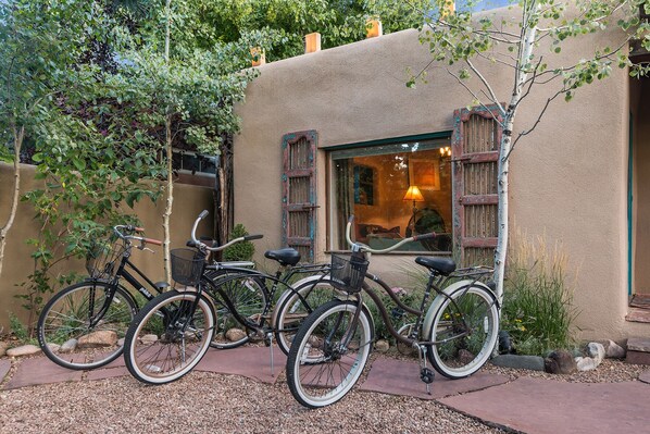 A building with a rustic exterior, a window with wooden shutters, and two bicycles parked in front.