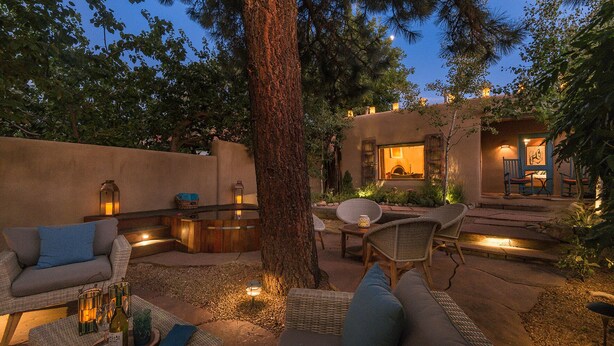 Un espacio al aire libre con mobiliario de mimbre, una mesa de piedra e iluminación ambiental.