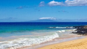 A beach with clear blue water, a sandy shore, and a distant mountain. - Time Beach @ Grand Van Kleef  (Kihei)