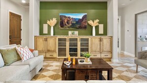 Un salon avec un mur d’accent vert, un grand tableau encadré, des meubles en bois, une table basse et un canapé.