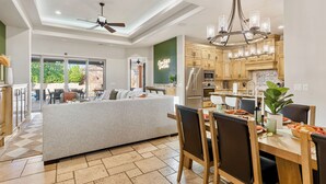 Une cuisine spacieuse dotée d’appareils électroménagers modernes, un coin repas avec un grand îlot central et un ventilateur de plafond.