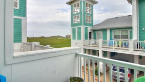 Una casa costera con balcón, una pequeña estructura parecida a una torre y vista a la playa.