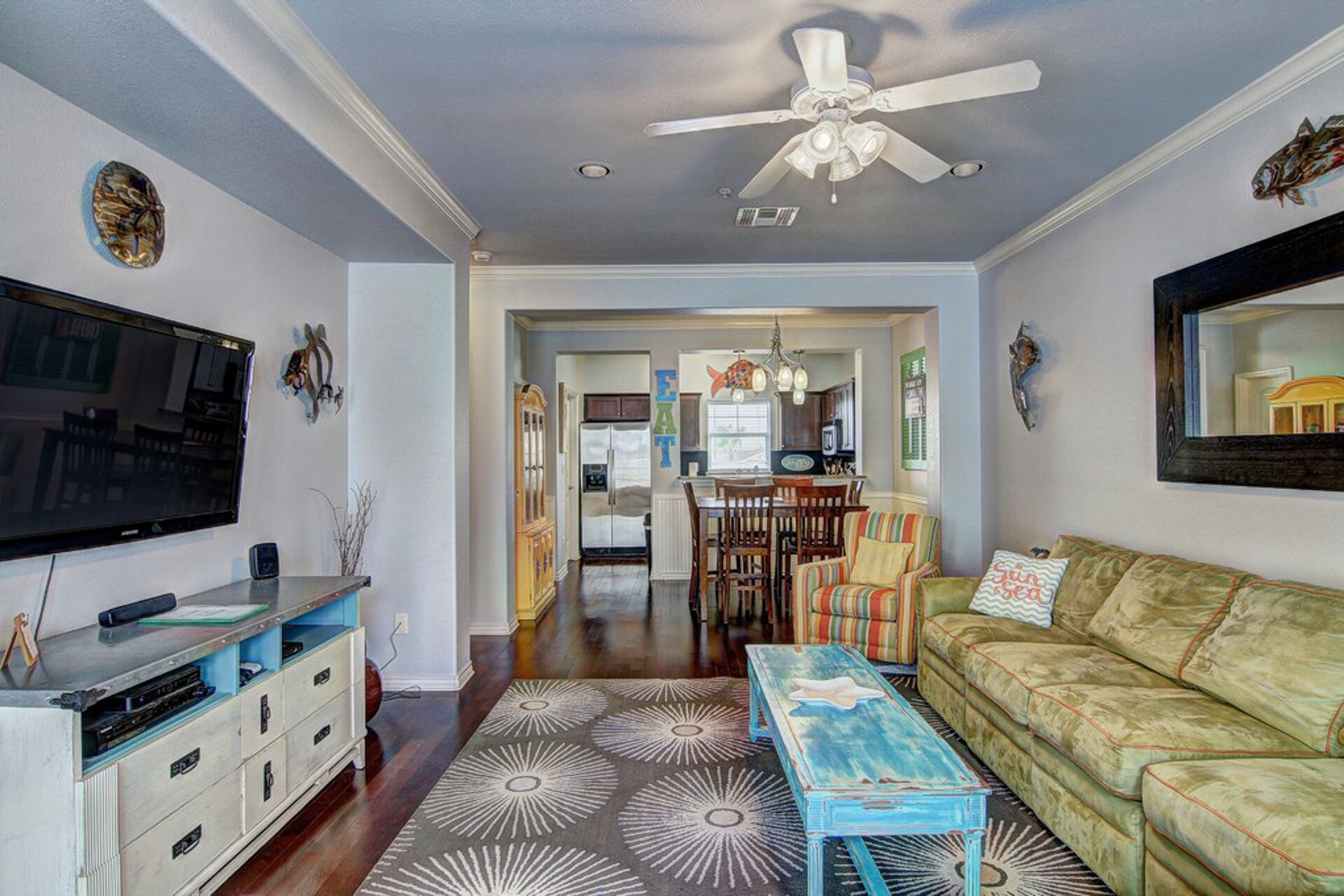 A living room with a television, a sofa, a coffee table, and a ceiling fan.