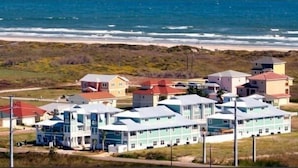 Zona residencial costera con varias casas, algunas con tejados rojos y otras con tejados azules, ubicada cerca de la playa.