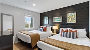 Una habitación de hotel con dos camas, un espejo grande, una ventana y obras de arte en la pared.