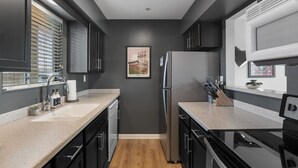 Una cocina moderna con paredes oscuras, suelo de madera y electrodomésticos de acero inoxidable.