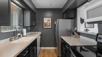 Une cuisine moderne avec des murs de couleur foncée, un plancher en bois et des appareils électroménagers en acier inoxydable.