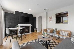 A modern living room with a fireplace, a dining area, and a seating area with a sofa and two armchairs.