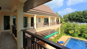 A hotel with a balcony overlooking a swimming pool and lush greenery. - Villa Mukdara (Rawai)