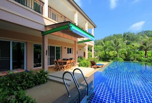 Uma casa moderna com piscina, móveis de exterior e vegetação exuberante.