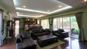 A spacious living room with a large sofa, a coffee table, and a dining area with chairs. - Villa Mukdara (Rawai)